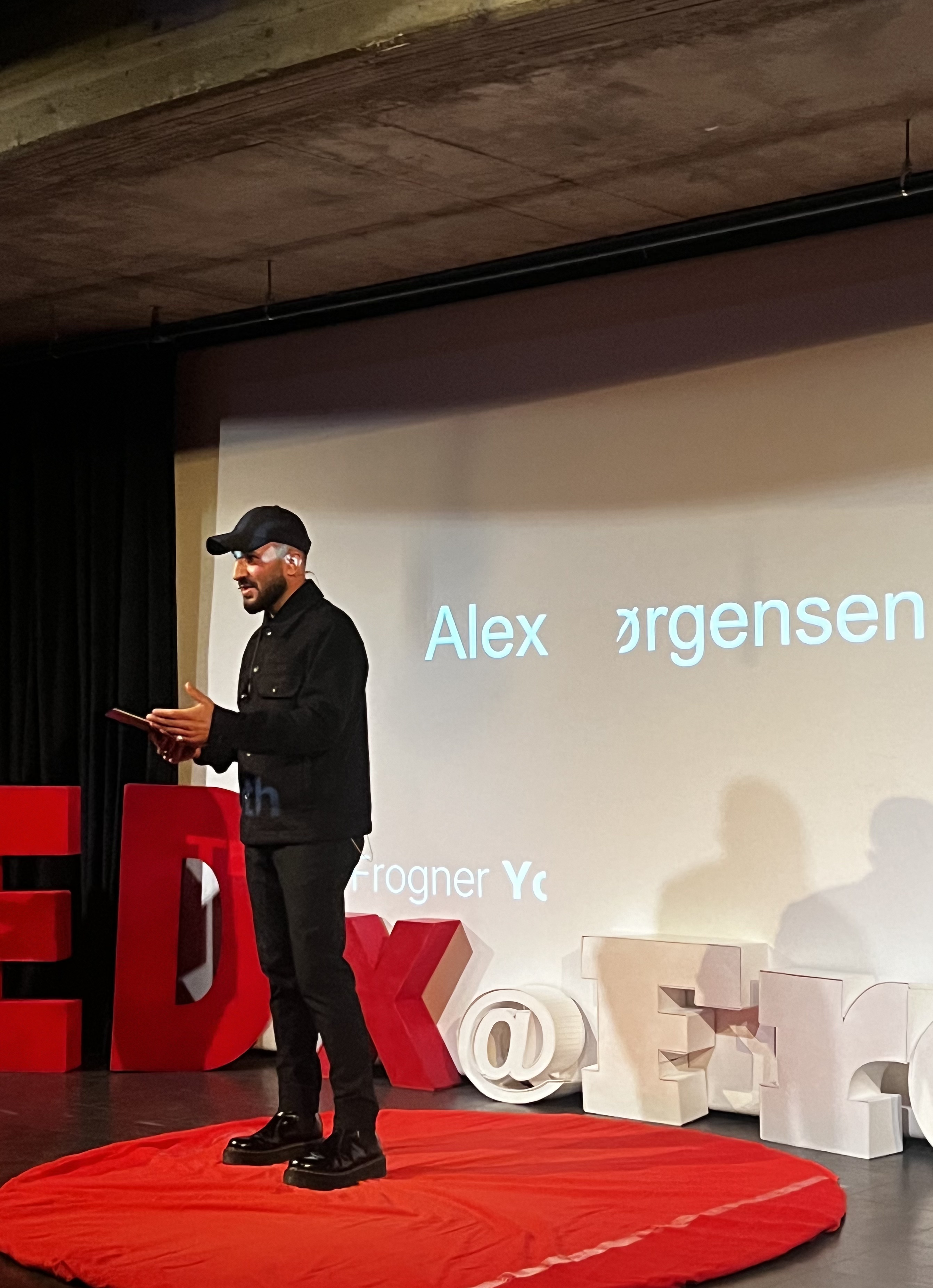 Alex Jørgensen delivering a TED Talk on stage.